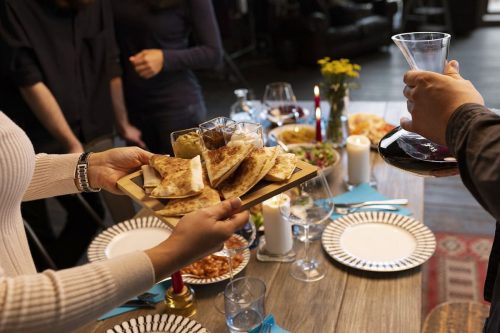 Photographie d'une personne proposant un plateau apéritif à un groupe autour d'une table