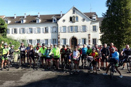 Photographie d'un grand groupe de cyclistes, souriant devant la caméra