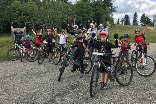 Photographie d'un groupe d'enfant à vélo, les bras en l'air, souriant pour une photo
