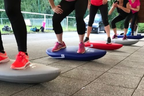 Photographie du groupe de l'activité Fit Training en train de réaliser des squats sur une planche instable