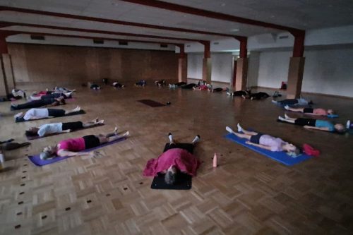 Photographie d'un groupe de l'activité Pilates en intérieur sur des tapis de yoga, allongés au sol