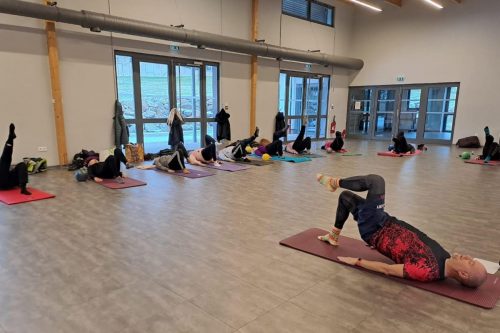 Photographie d'un groupe de l'activité Pilates en intérieur sur des tapis de yoga