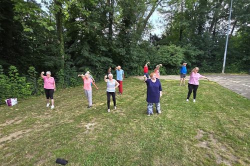 Photographie d'un groupe de l'activité Qi Gong en extérieur, avec la forêt en fond