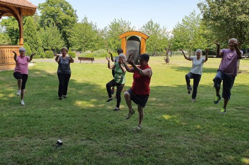 Photographie d'un groupe de l'activité Qi Gong en extérieur, dans une position sur un seul pied