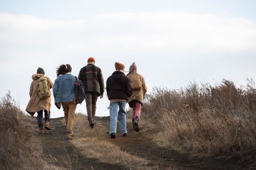 Photographie d'un groupe de randonneurs vus de dos, en train de monter un sentier de montagne.
