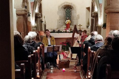 Photographie d'un concert se tenant dans une église, le groupe joue de la harpe et chante.