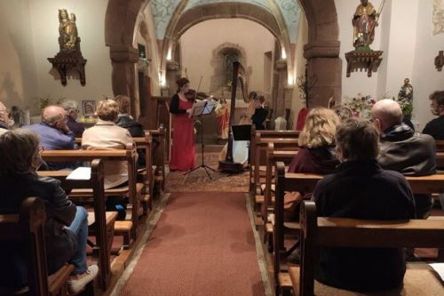 Photographie d'un concert dans une église avec une violoniste et une harpiste.
