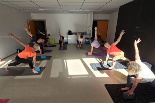 Photographie d'un groupe pendant l'activité Yoga dans la position Trikanasana
